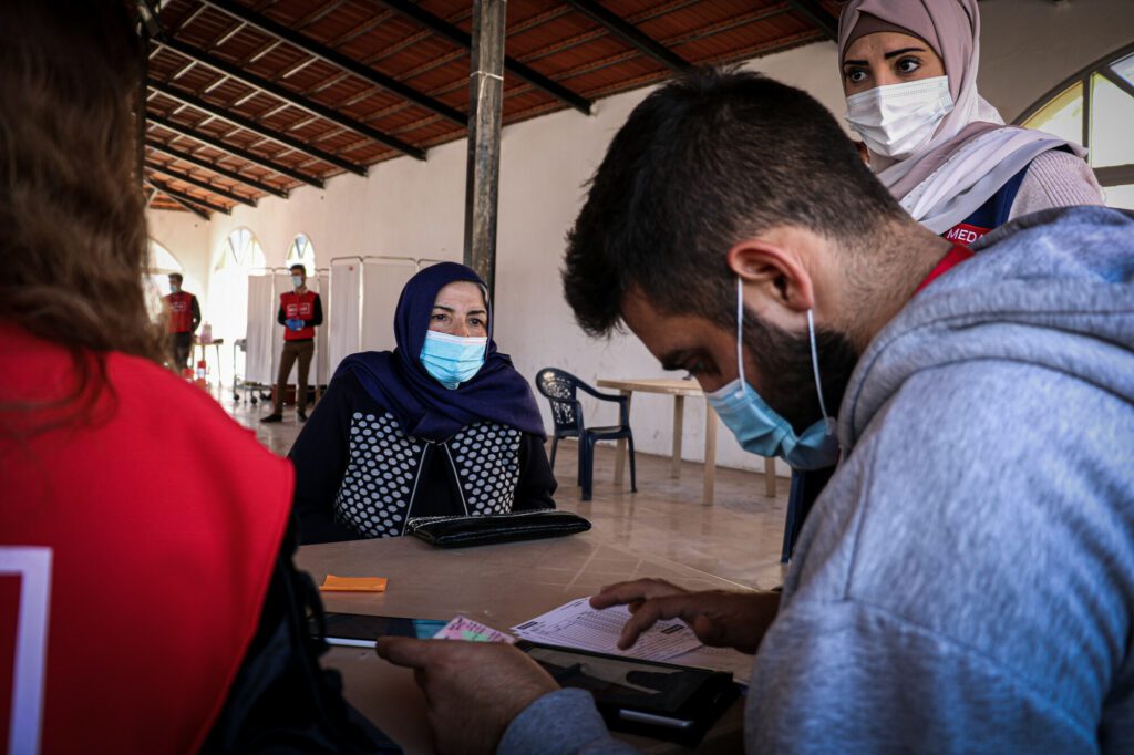 Een Libanese vrouw wacht terwijl een Medair-medewerker haar registratie controleert.