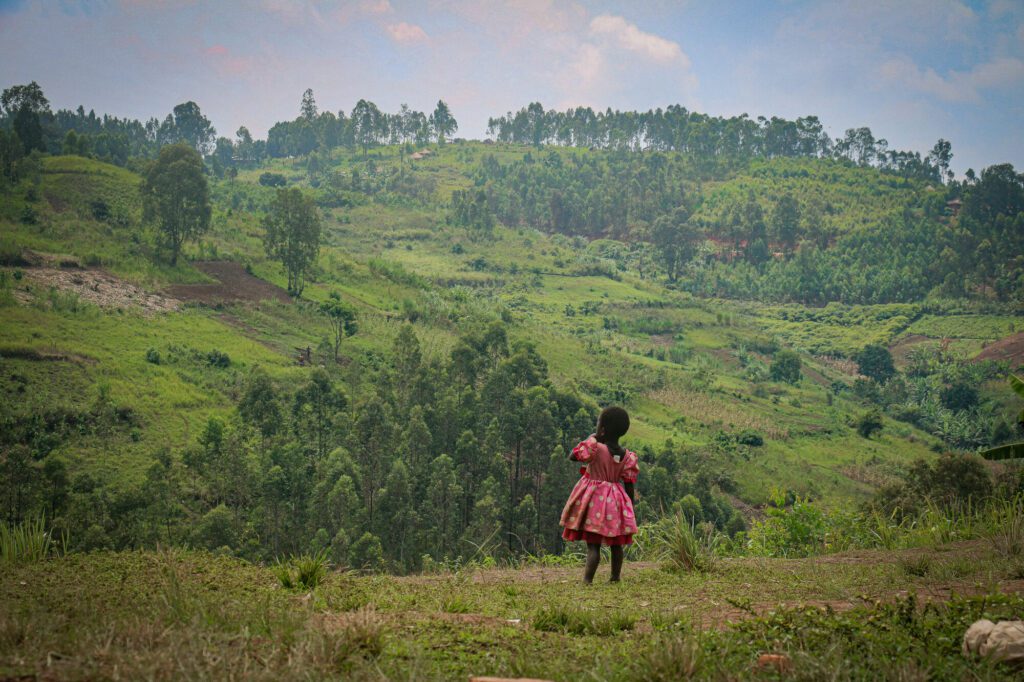 Ein Mädchen blickt auf die sie umgebenden grünen Hügel in der Provinz Ituri, DR Kongo