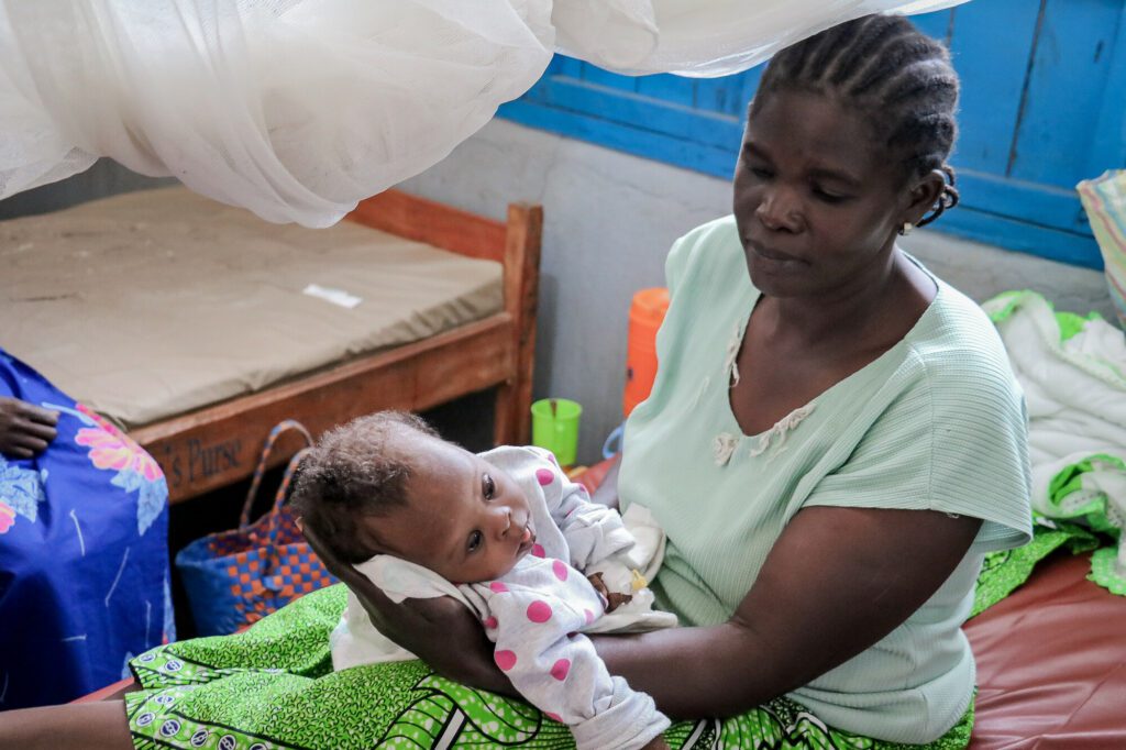 In a Medair health centre a Congolese woman holds her baby girl, approximately nine months old. The baby is unable to hold her head up on her own.