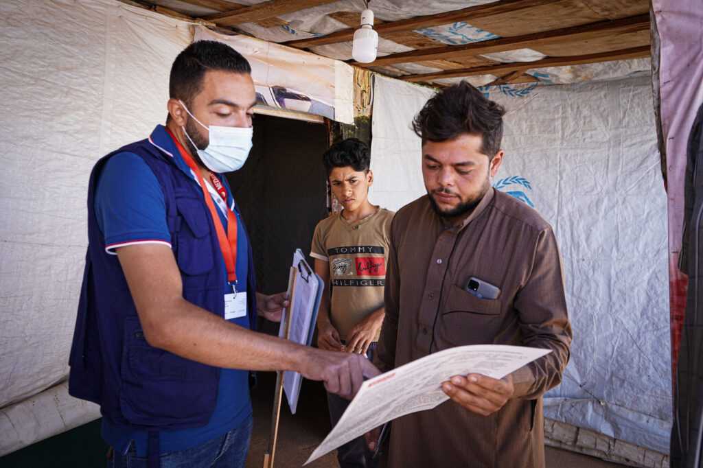A male humanitarian showing a Syrian community member a communication to community pager.