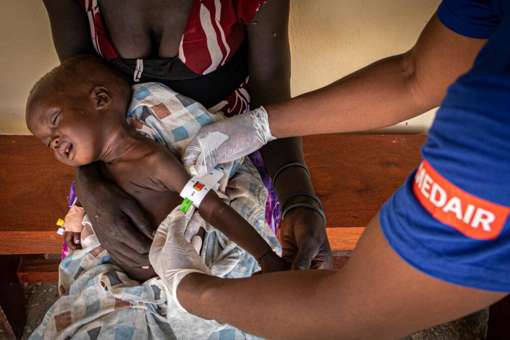 A male humanitarian worker treats a malnourished baby.