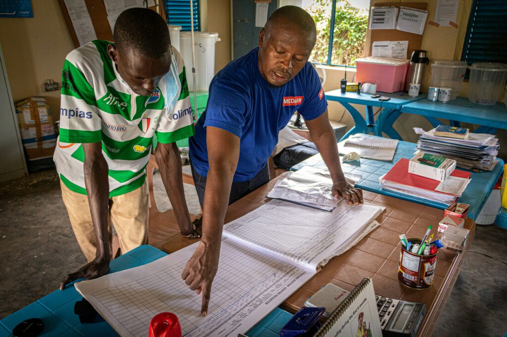 Two male humanitarian workers compile a treatment plan in a stabilization centre.