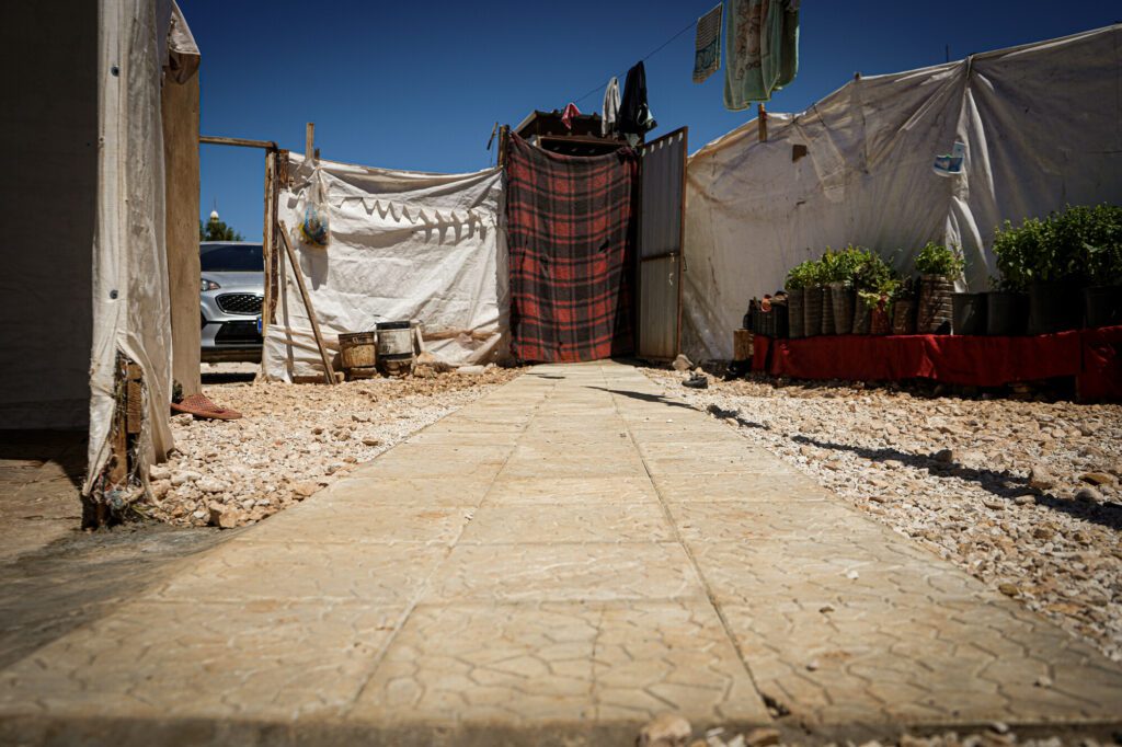 A cemented pathway leading to the bathroom in a tented settlement