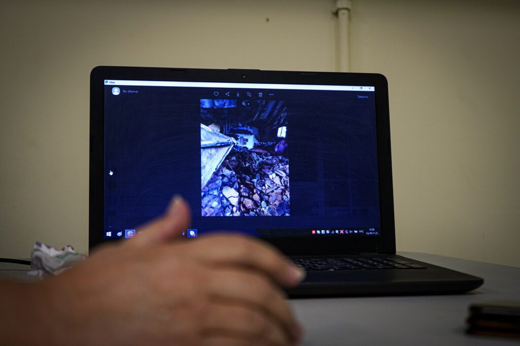 A photo of a destroyed home is displayed on a laptop screen.