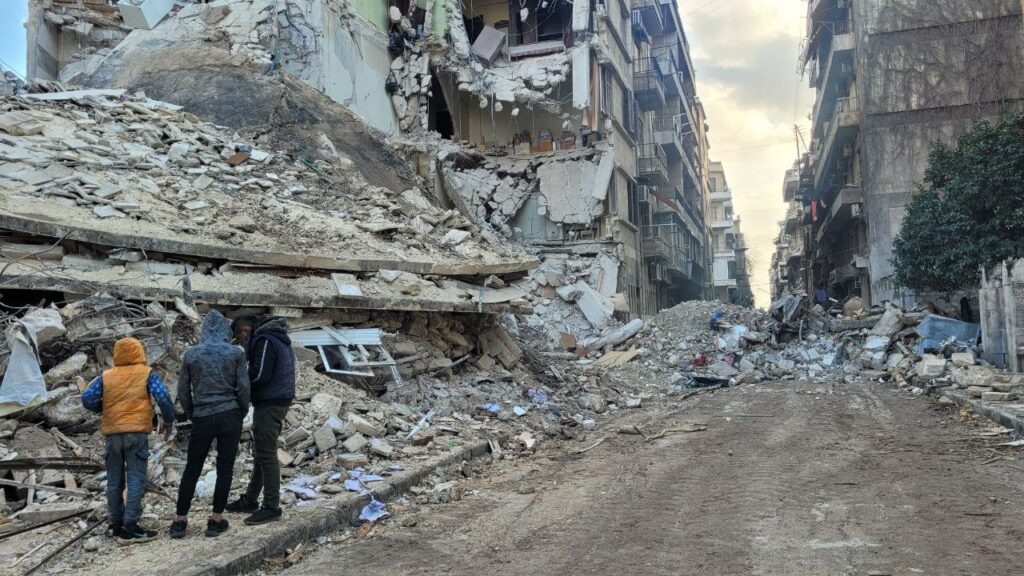  A group of men stand in front of a collapsed building in Aleppo, Syria.