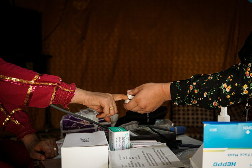  A female primary caregiver checks the blood pressure of an affected community member in a tented home.