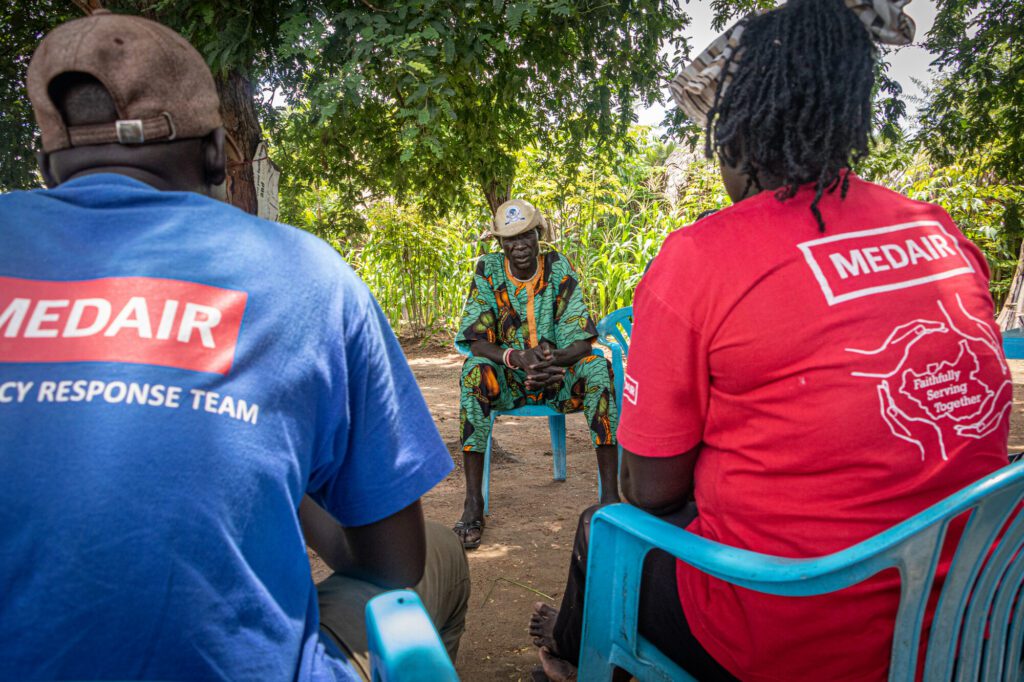 Humanitarian aid workers and a local community leader in talking to each other in South Sudan