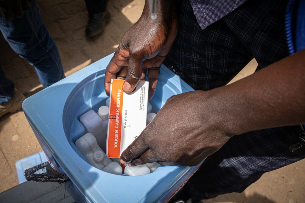 A humanitarian aid worker putting measles vaccines into a cooling box in South Sudan.