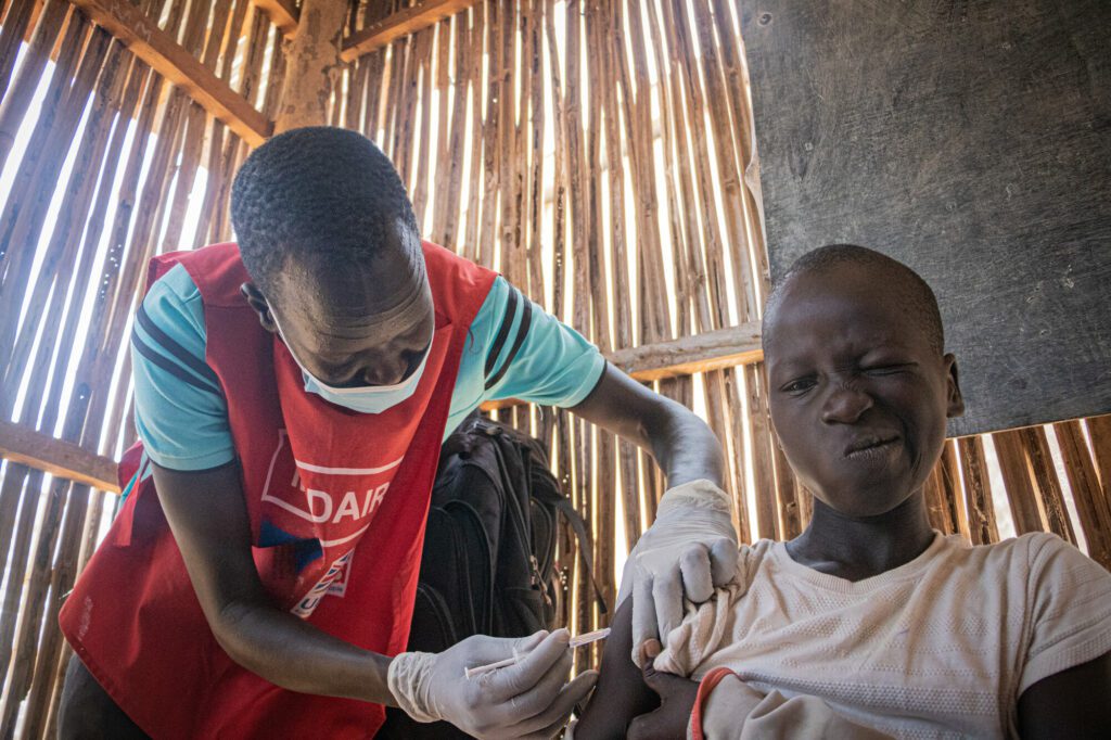 Humanitarian aid worker vaccinates a school boy against measles