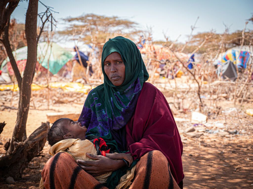 A women holding a crying malnourished child in an IDP settlement in Southern Somalia