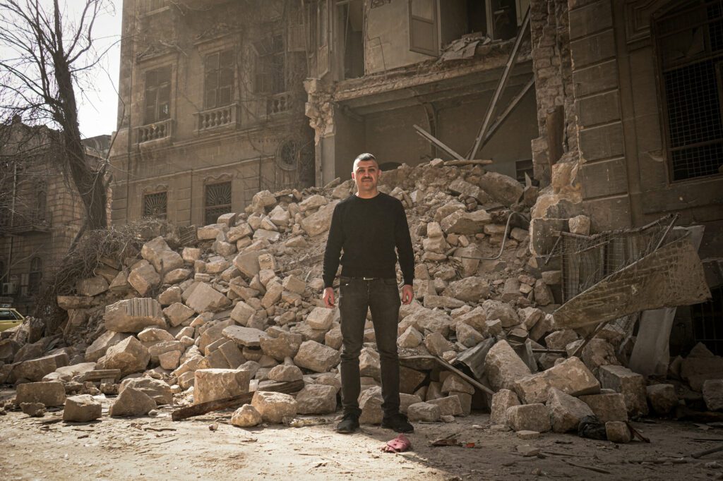 A man stands in front of a collapsed building in Aleppo caused by devastating Syria - Türkiye earthquakes.
