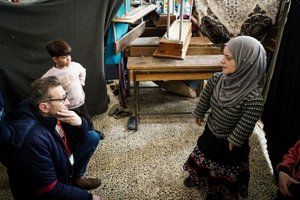 A humanitarian aid worker speaks with an affected Syrian community member.