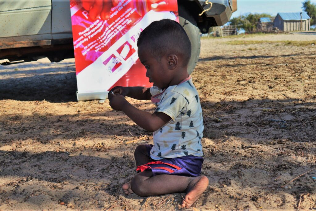 Ein zweijähriger madagassischer Junge spielt neben der mobilen Klinik einer humanitären NGO, nachdem er erfolgreich gegen Unterernährung behandelt worden ist.