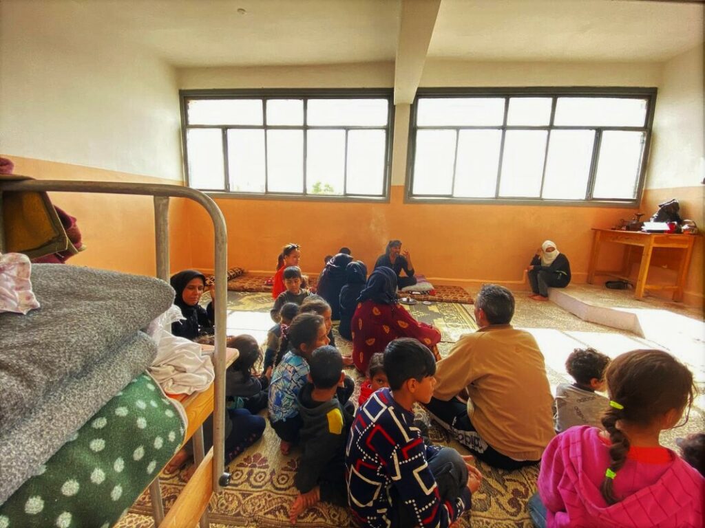 Mehrere Familien mit Kindern sitzen in einem Klassenzimmer der Al-Takadum-Al-Arabi-Schule im Stadtteil Al Salheen in Aleppo, die in eine Sammelunterkunft umgewandelt wurde. 