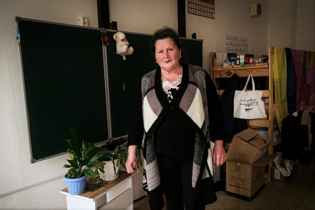 Valentyna is standing near the board in a classroom which is used as sheleter for IDPs