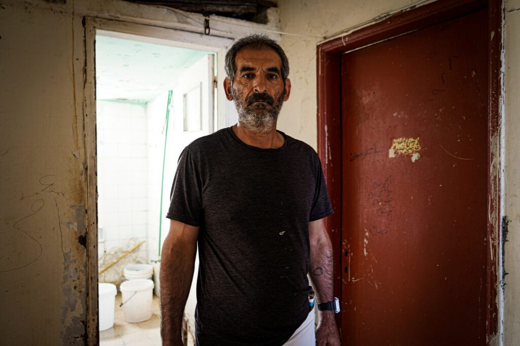 A Syrian man stands in his home.