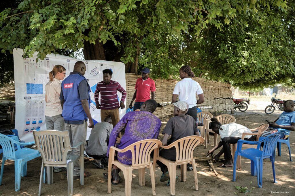 Humanitarian aid workers and members of a community in Juba, South Sudan, are going through instructions to assemble a flood resilient shelter.