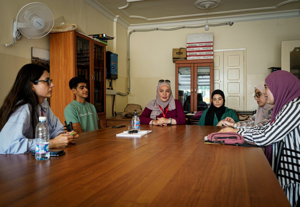 Adolescents sit at a desk during a group session with facilitators.