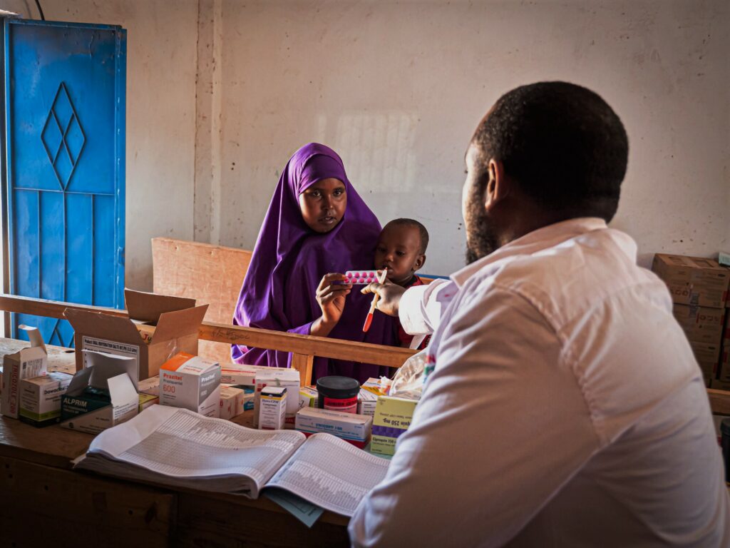 A male clinical staff hands over drugs to a mother and her infant in a pharmacy in southern Somalia.
