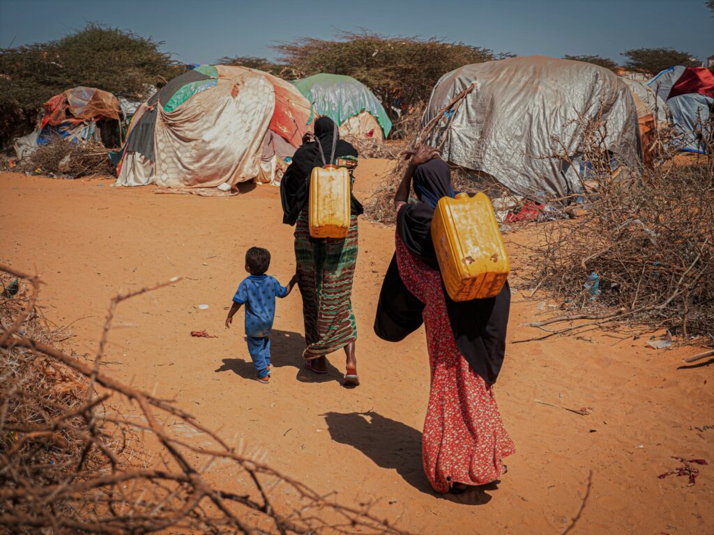 Two women and an infant walking in a informal settlement for displaced people in southern Somalia.