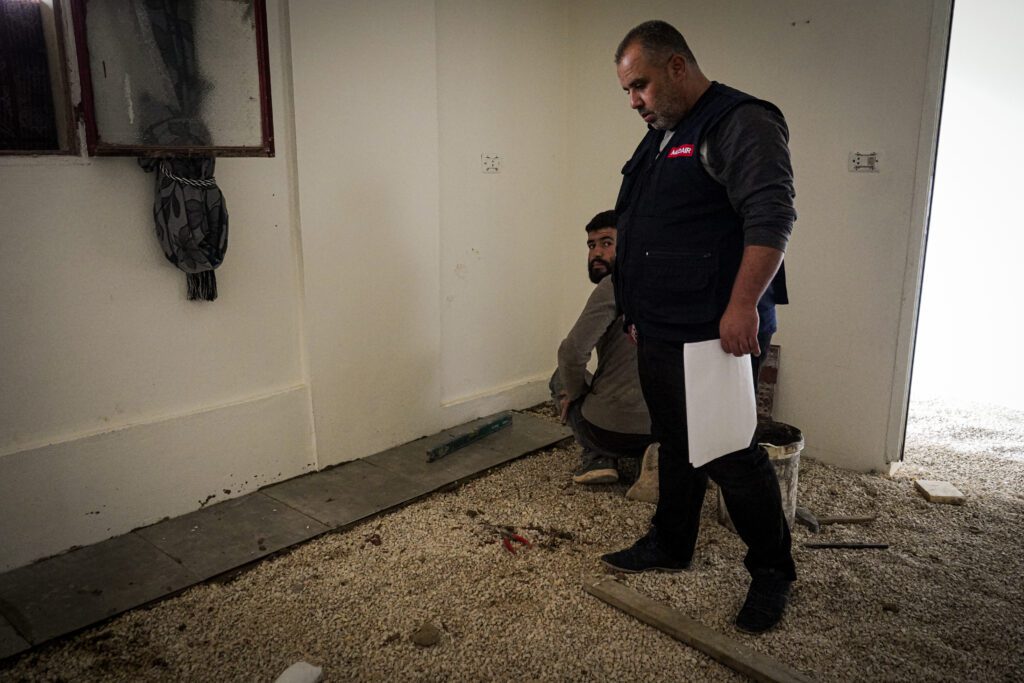 Un travailleur humanitaire surveille le travail des entrepreneurs dans un bâtiment insalubre.