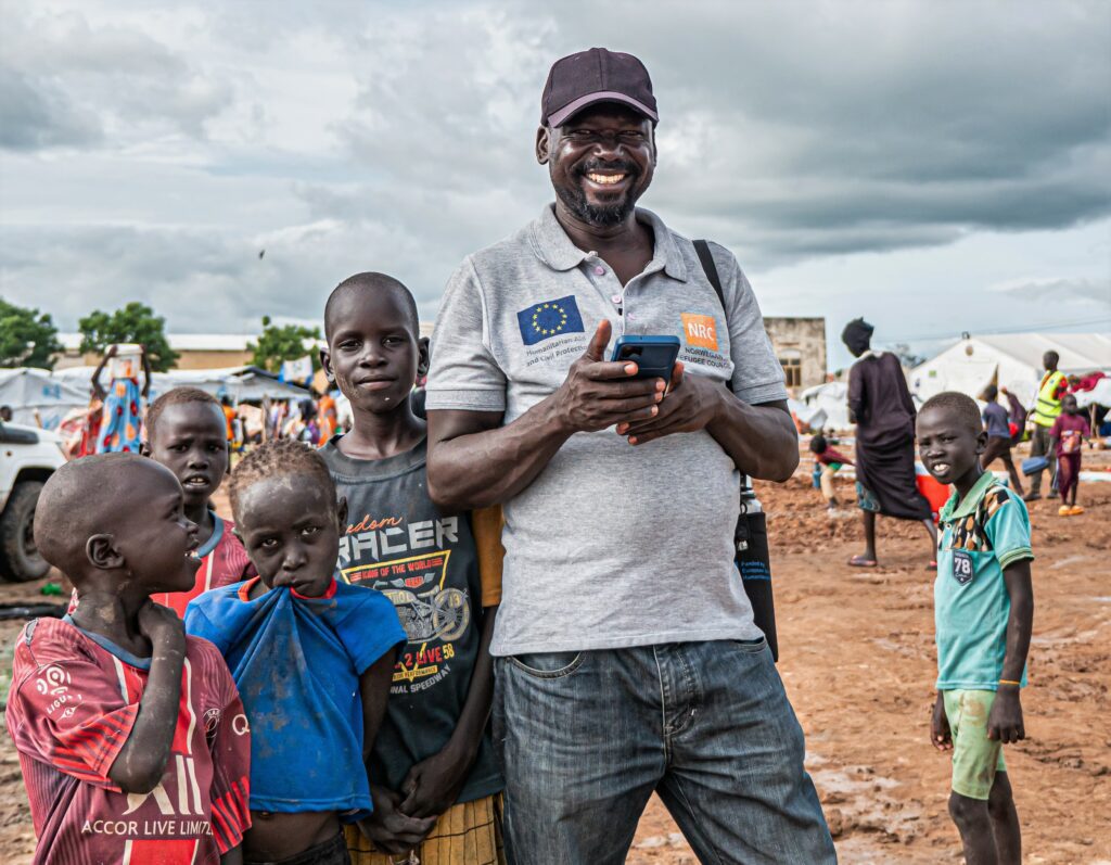 A humanitarian aid worker with children of a returnee community in a Transit Center in Renk town, South Sudan.