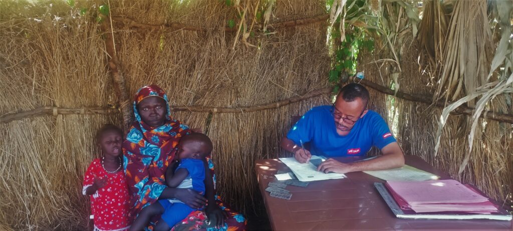 Een vrouw met twee kinderen en een mannelijke noodhulpwerker tijdens behandeling in een gezondheids- en voedingscentrum in de staat Blue Nile in Soedan.